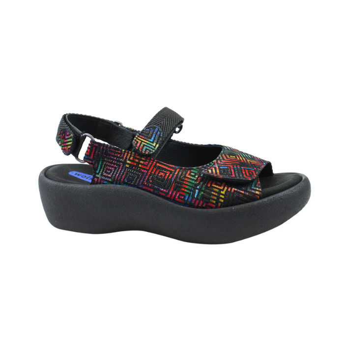 Geometric rainbow platform sandal with a closed side, open back, open toe, and adjustable hook-and-loop straps across the top and around the ankle.