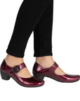 Burgundy shoes with a black buckle worn with black pants.