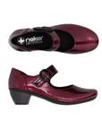 Pair of burgundy patent leather heeled shoes with a black strap buckle and black footbed with the Rieker logo.