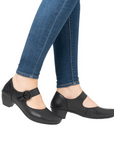 Black shoes with a buckle worn with blue jeans.