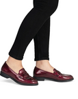Dark red patent loafers worn with black pants.