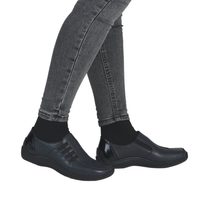 Navy slip-on shoes worn with grey jeans.