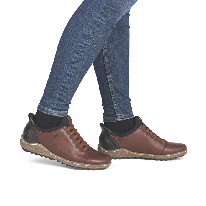 Brown leather shoes worn with blue jeans and black socks.