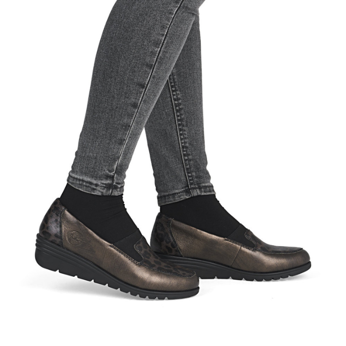 Bronze wedge shoes worn with gray jeans.