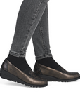 Bronze wedge shoes worn with gray jeans.