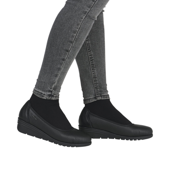 Black slip-on low wedge shoes worn with gray jeans.