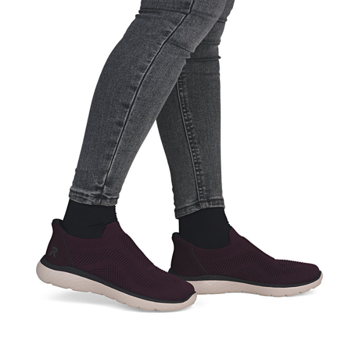 Burgundy slip-on shoes worn with gray jeans and black socks.