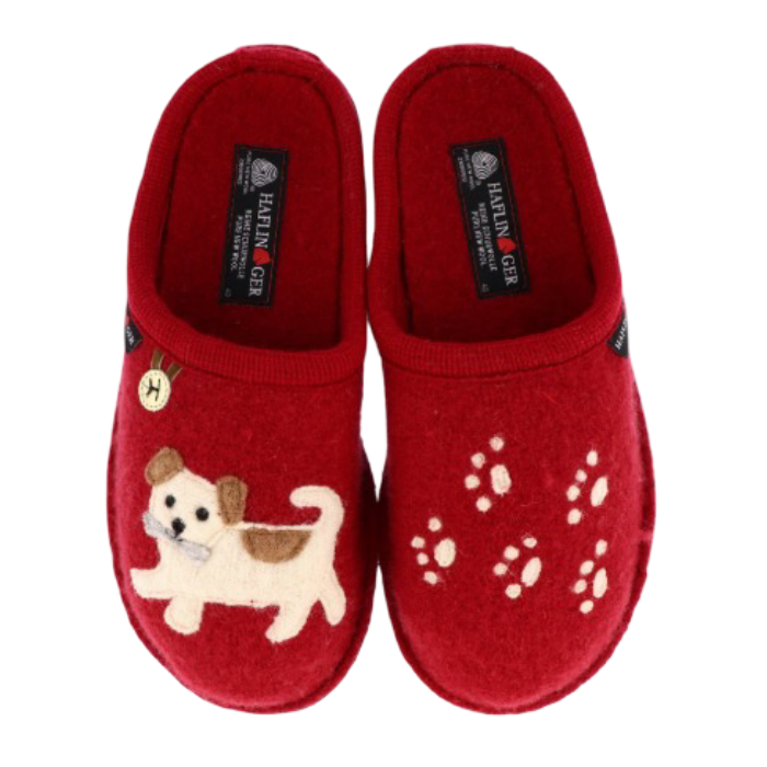 A pair of red felt slip-on slippers with a small embroidered dog on one slipper and white paw prints on the other and  Haflinger tag on the footbed.