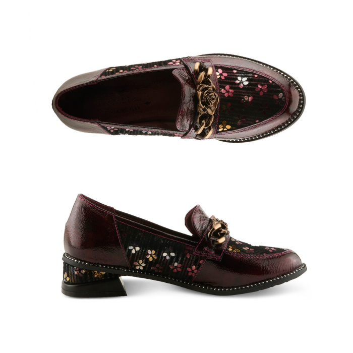 Pair of glossy burgundy leather loafers with floral pattern on the side panels, a decorative burnished gold metal rose on chain embellishment on the vamp, and black sculptured low block heel.
