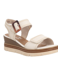 Beige wedge sandal with brown buckle, accent zig-zag stitching, tan Remonte logo'd footbed and off-white outsole.