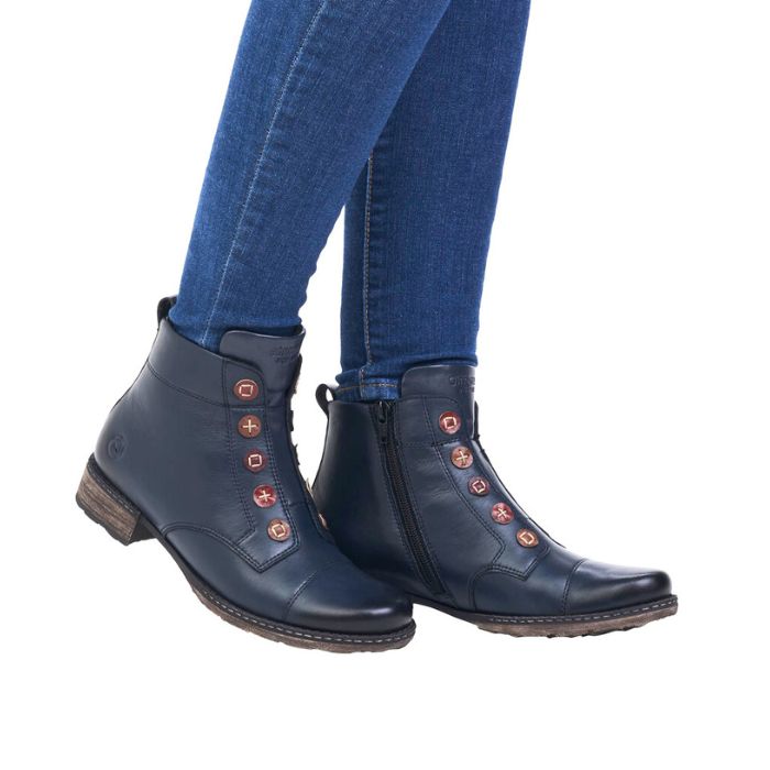 Legs in jeans wearing navy ankle boot with button details on front and low heel. Black inside zipper closure.
