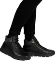 Black high-top sneakers with leopard print accents worn with black pants.