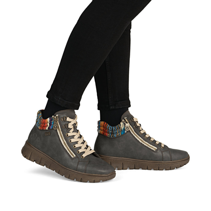 Gray ankle boots with colorful cuff worn with black pants.