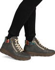 Gray ankle boots with colorful cuff worn with black pants.