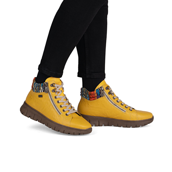 Yellow boots with colorful accents worn with black pants.