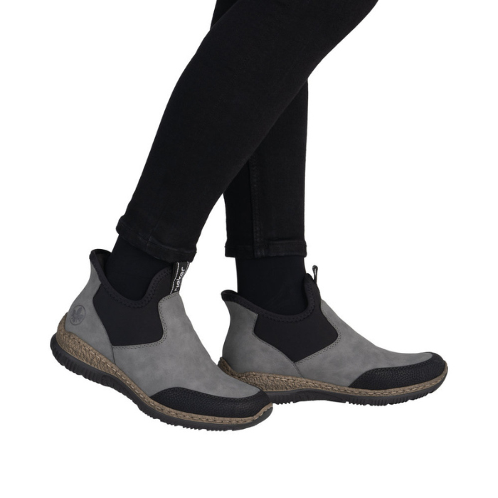 Gray and black ankle boots worn with black pants.