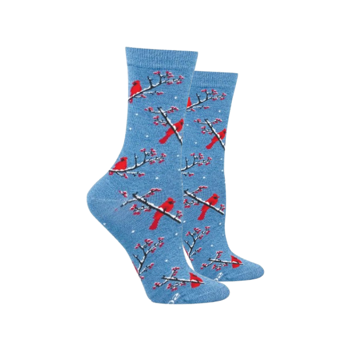 A pair of crew socks in heathered light blue with a winter pattern of red cardinals on snow-covered branches and small white snowflakes.