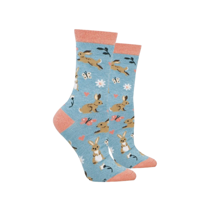 A pair of crew socks with a light blue background featuring a pattern of cute bunnies, butterflies, and small flowers, finished with peach-colored cuffs, heels, and toes.