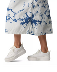 White sneakers worn with a white with  blue tie-dye skirt.