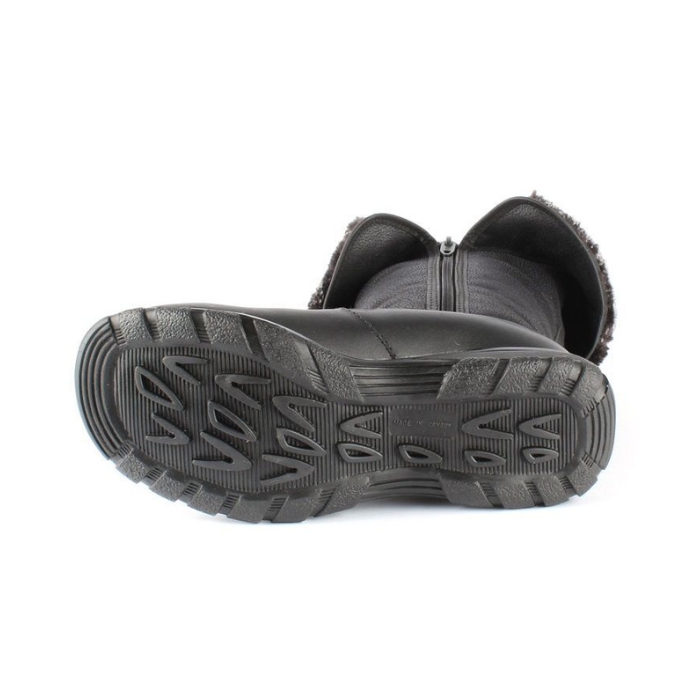 Black treaded outsole of tall boot on its side with inside zipper and folded down cuff.