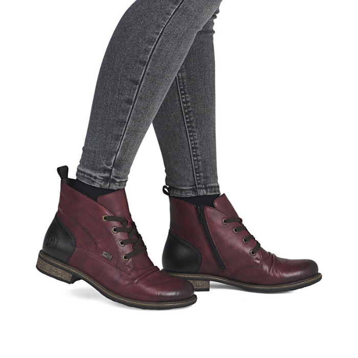 Maroon boots with black accents worn with gray jeans.