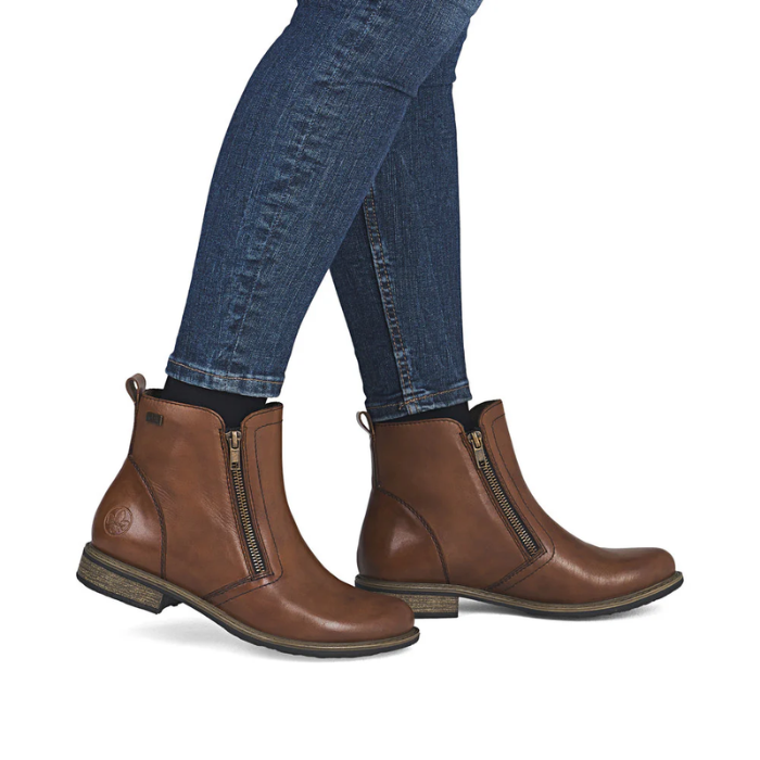 Brown leather boots with zippers worn with blue jeans.