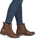 Brown leather boots with zippers worn with blue jeans.