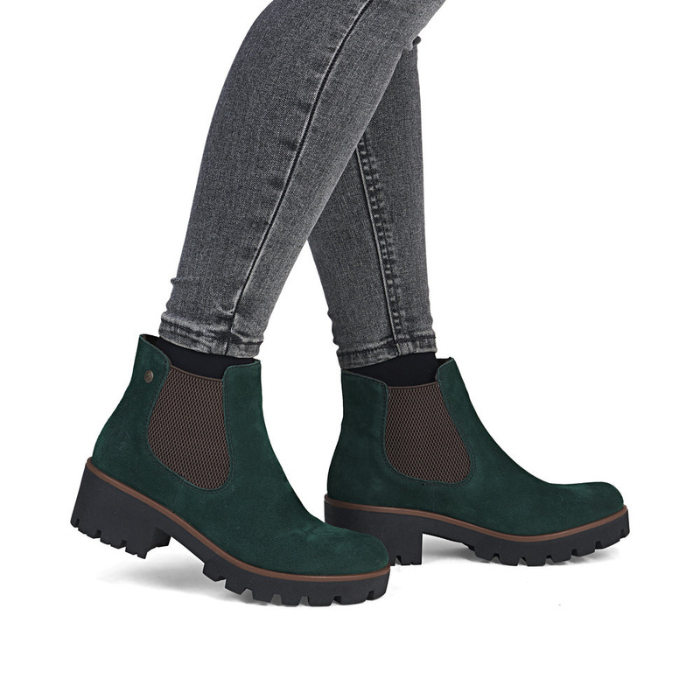 Green Chelsea boots worn with gray jeans.