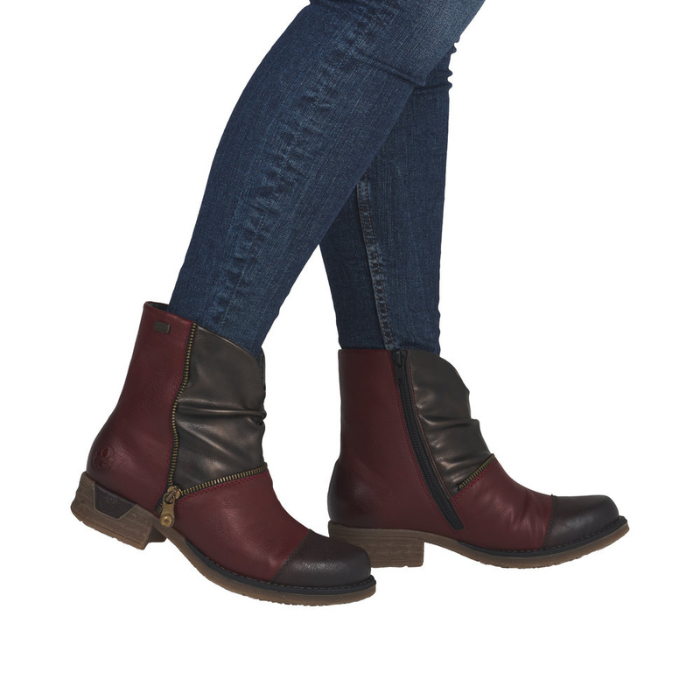 Woman wearing red and bronze ankle boots with accent zipper in blue jeans.
