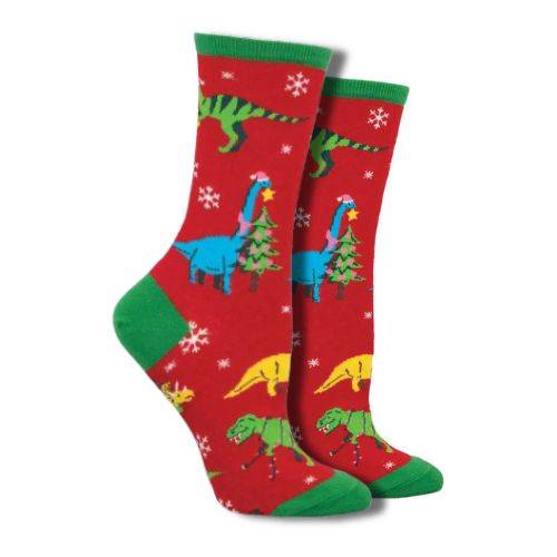 Socksmith Women's The First Christmas Socks featuring colorful dinosaurs in Santa hats and Christmas trees on a red background with green accents. Perfect holiday-themed crew socks available at White-Balmer Shoes.