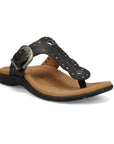 Black T-strap sandal with embroidery, rivets and grommet detailing and an antiqued adjustable buckle with beige footbed and black outsole.