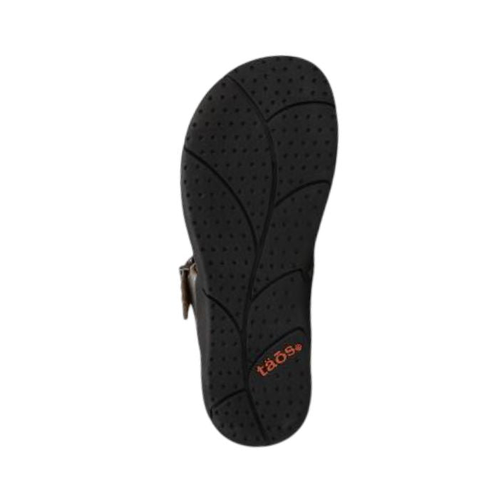 Black outsole with leaf pattern tread and Taos logo near heel.