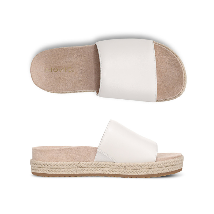 Pair of white slide espadrille sandals with Vionic logo'd tan footbed.