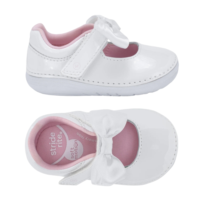 Pair fo A white patent leather baby Mary Jane shoes with a white satin bow on the strap and a pink interior lining.