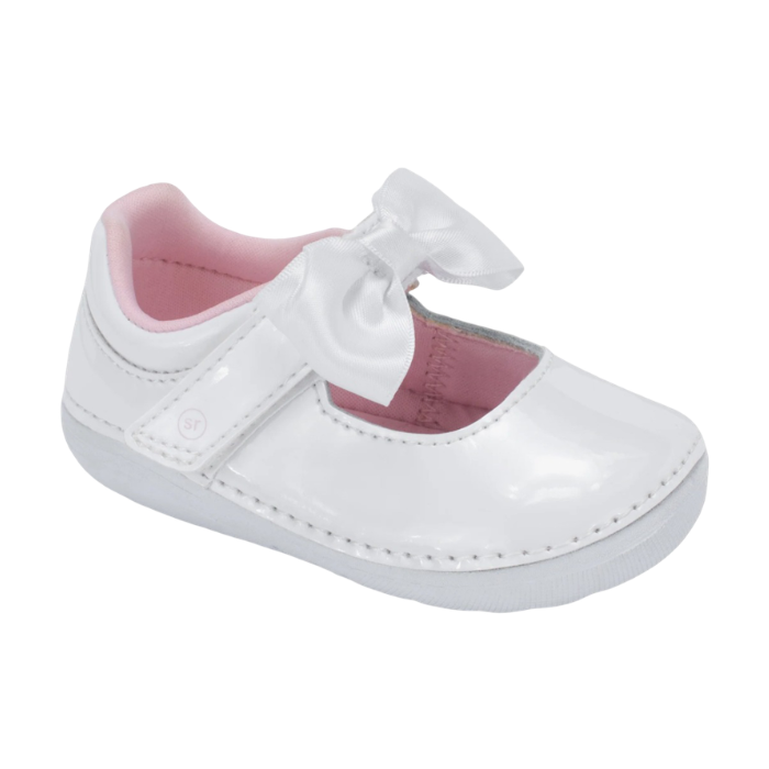 A white patent leather baby Mary Jane shoe with a white satin bow on the strap and a pink interior lining.