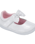 A white patent leather baby Mary Jane shoe with a white satin bow on the strap and a pink interior lining.
