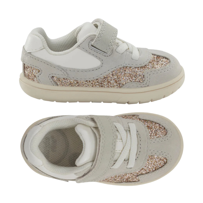 Pair of A toddler's light gray sneakers with a glittery gold and silver side panel, white elastic lacing, and a hook-and-loop strap closure.