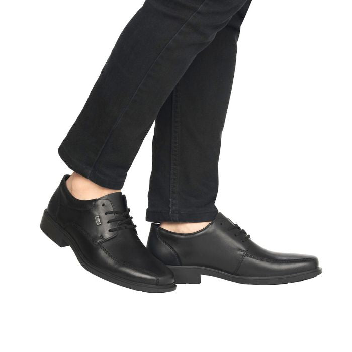Legs in black jeans wearing black leather dress shoe with bicycle toe.