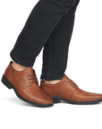 Legs in black jeans wearing brown leather dress shoe with bicycle toe.