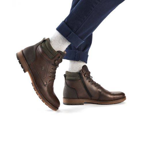 Model wearing brown men's lace-up ankle boots with side zipper, styled with rolled up blue jeans.