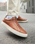 Brown leather sneaker with lace closure and white outsole.