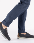 Dark blue slip-on shoes worn with navy pants.