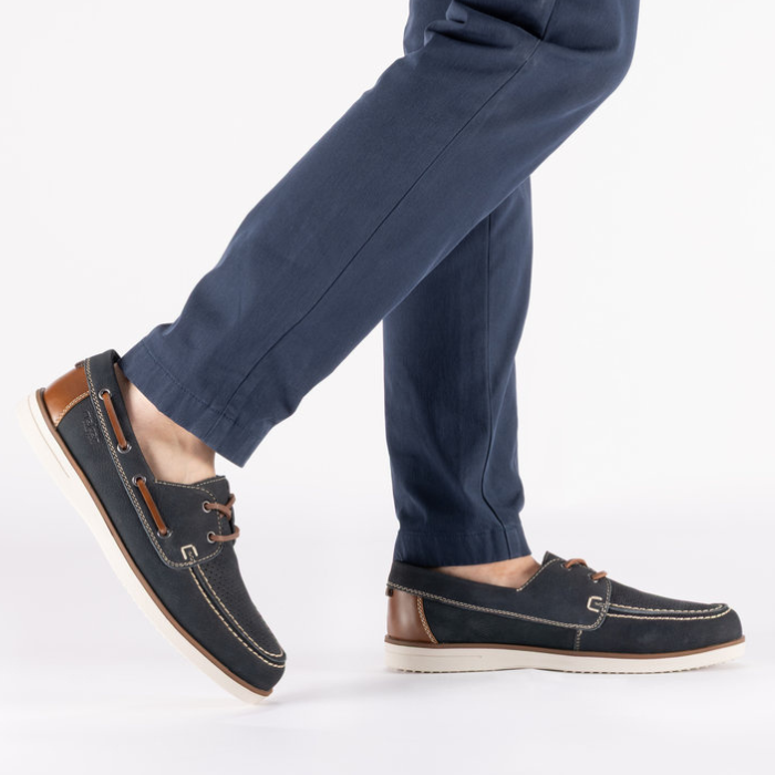 Navy blue boat shoes with brown accents worn with navy pants.