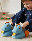 Child wearing dragon-themed slippers on a carpeted floor with toys in the background.