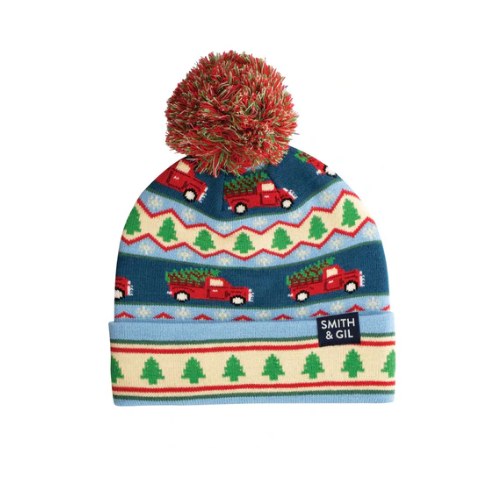 Knitted hat with red pom-pom, Christmas tree pattern, and red trucks and tag with Smith & Gil logo.