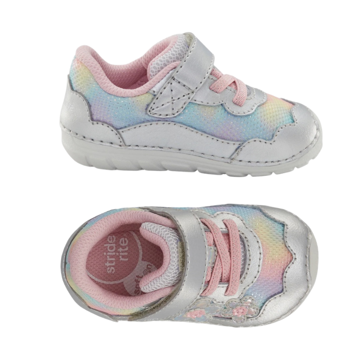 A pair of toddler's pastel rainbow mesh and silver leather sneakers with a hook-and-loop strap, pastel pink laces, and iridescent floral appliques on the side, pink footbed and white outsole.