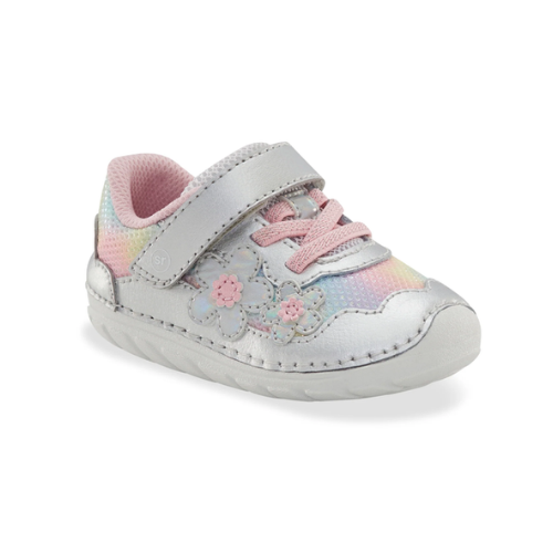 A toddler's pastel rainbow mesh and silver leather sneaker with a hook-and-loop strap, pastel pink laces, and iridescent floral appliques on the side and white outsole.