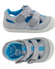 Pair of light grey toddler sandals with two hook-and-loop straps, blue accents, blue Stride Rite logo'd footbed and white outsole.