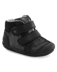 A black high-top baby bootie featuring a textured glittery black upper, a black knit ankle collar, and two wide black hook-and-loop straps.