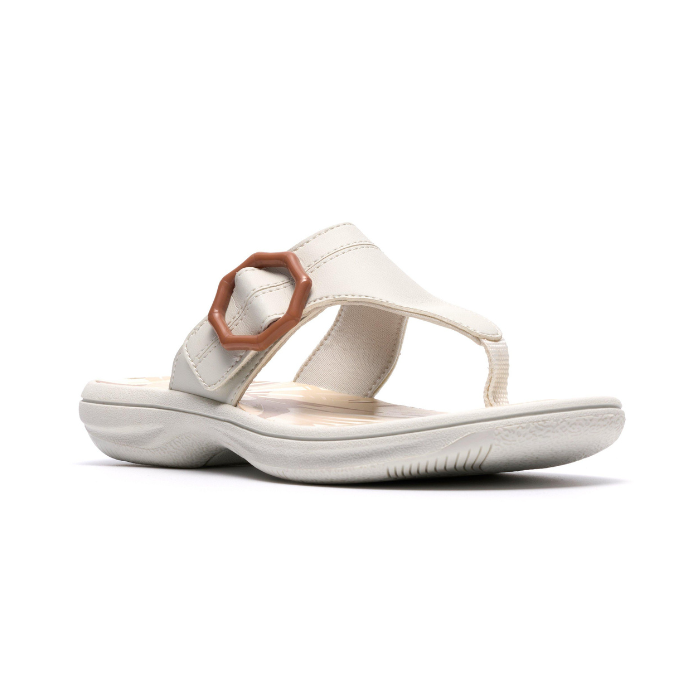 White thong sandal with a brown octagonal buckle, floral beige footbed and white outsole.